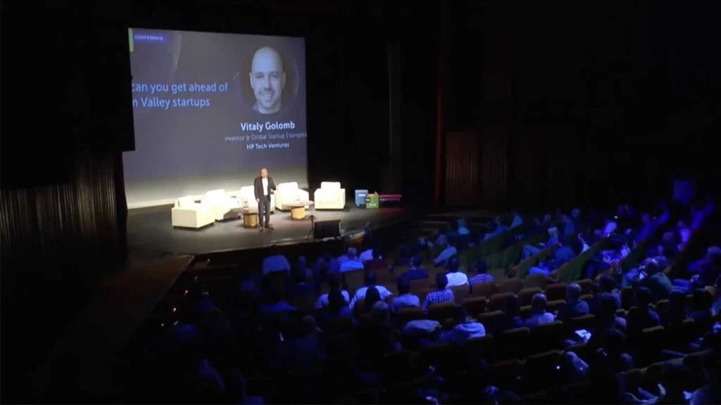 Vitaly giving a keynote to a seated conference audience